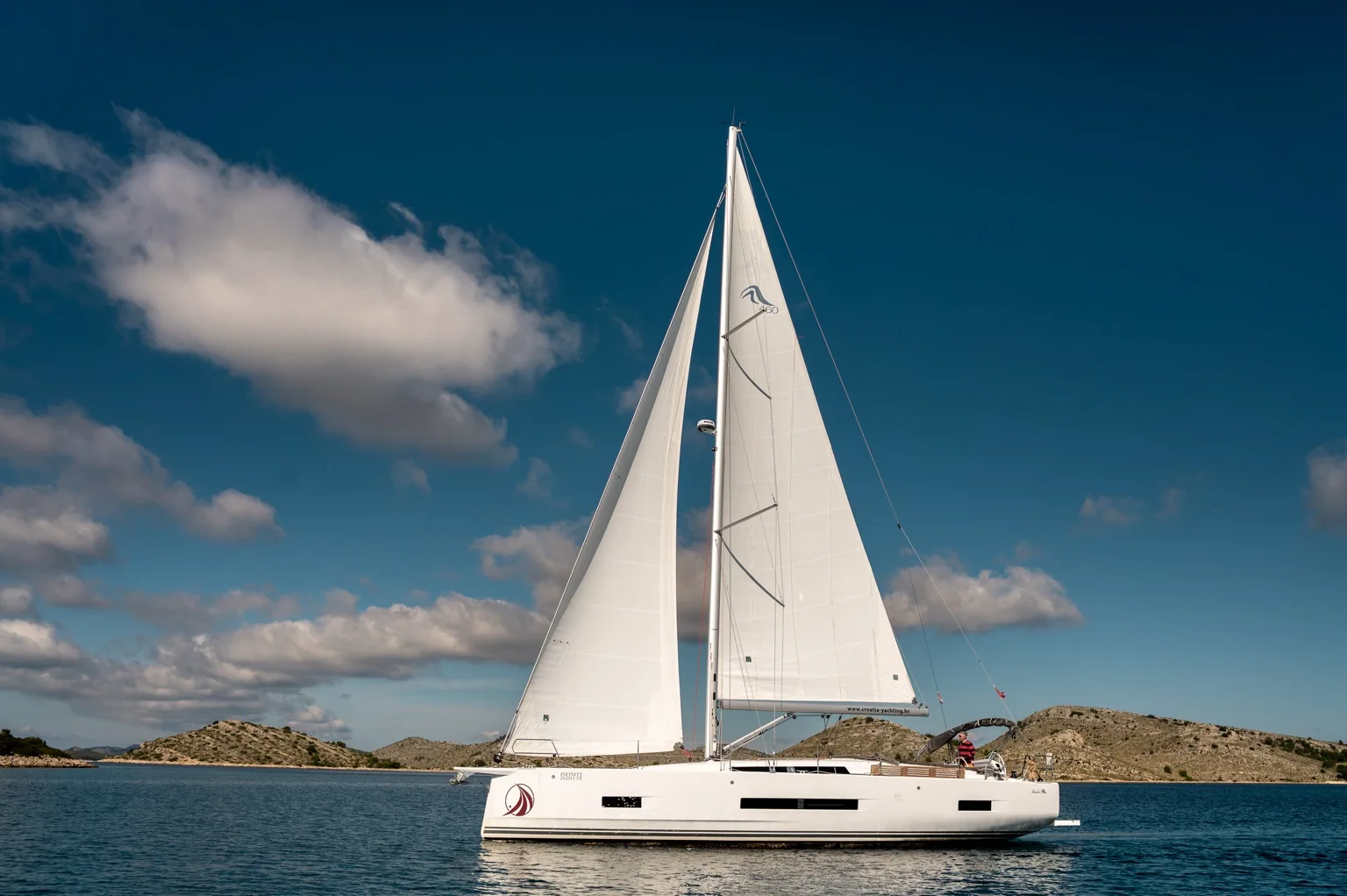 Infinity under full sail, with the full hull and mast visible